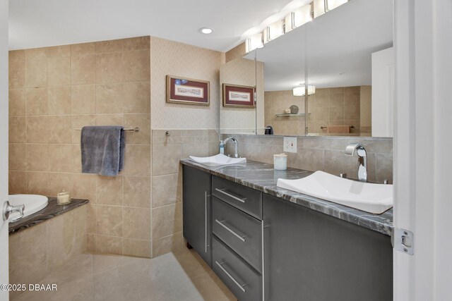 bathroom with vanity, tile walls, a washtub, and tile patterned floors