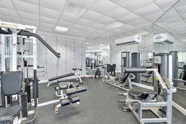 workout area with a wall mounted AC and a drop ceiling