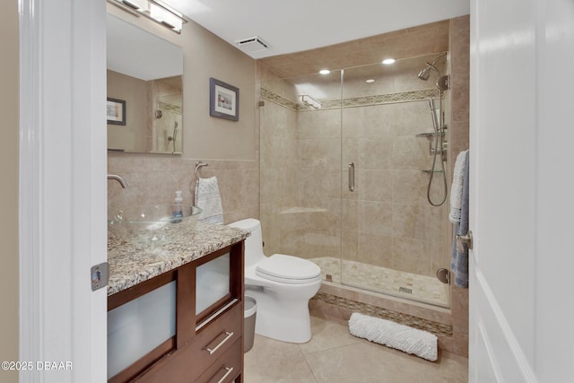 bathroom with vanity, a shower with shower door, tile patterned flooring, and tile walls