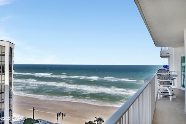 balcony with a water view and a view of the beach