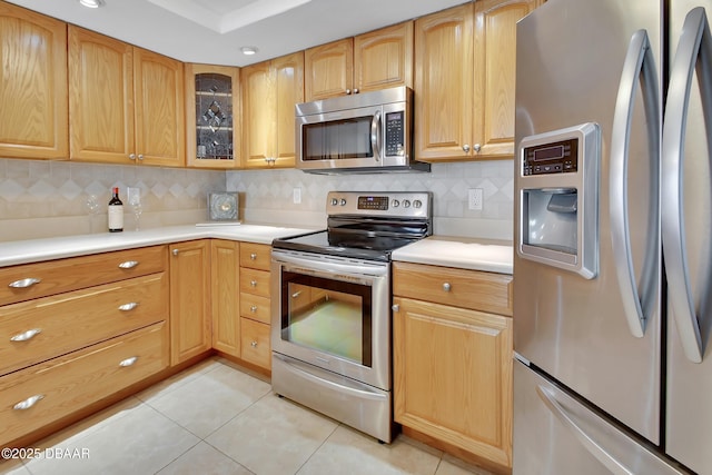 kitchen with backsplash, stainless steel appliances, and light tile patterned flooring