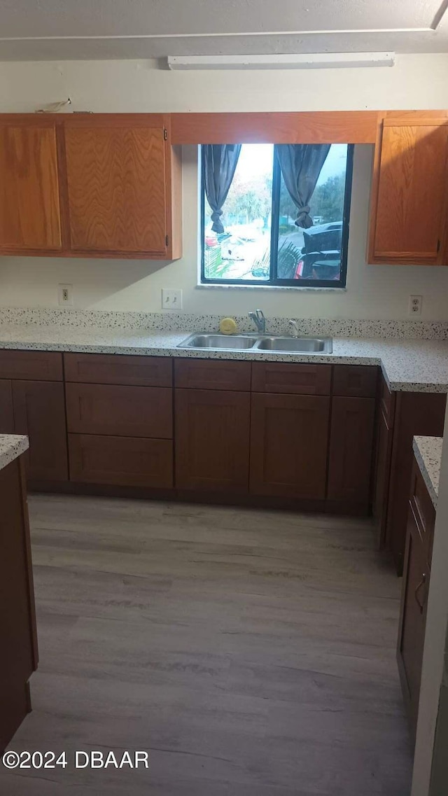 kitchen featuring a sink, light wood-type flooring, and brown cabinets