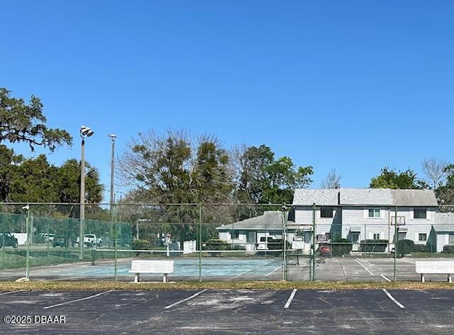 uncovered parking lot with a tennis court and fence