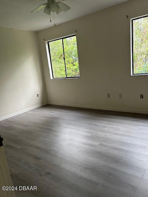 unfurnished room with wood finished floors, baseboards, and ceiling fan