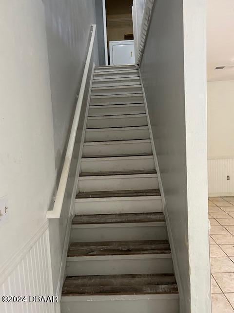 staircase featuring tile patterned flooring and wainscoting