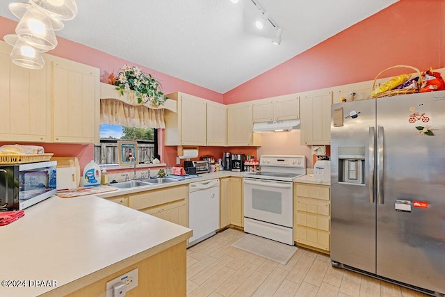 kitchen featuring hanging light fixtures, stainless steel appliances, track lighting, lofted ceiling, and sink