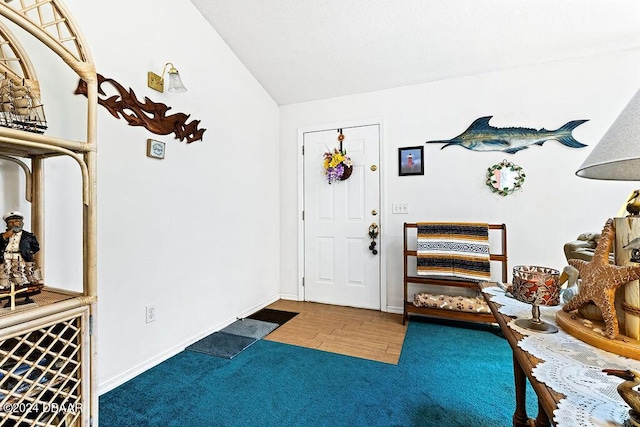 carpeted foyer entrance featuring vaulted ceiling