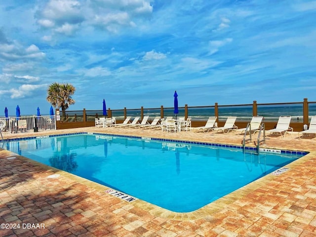 view of swimming pool with a patio and a water view