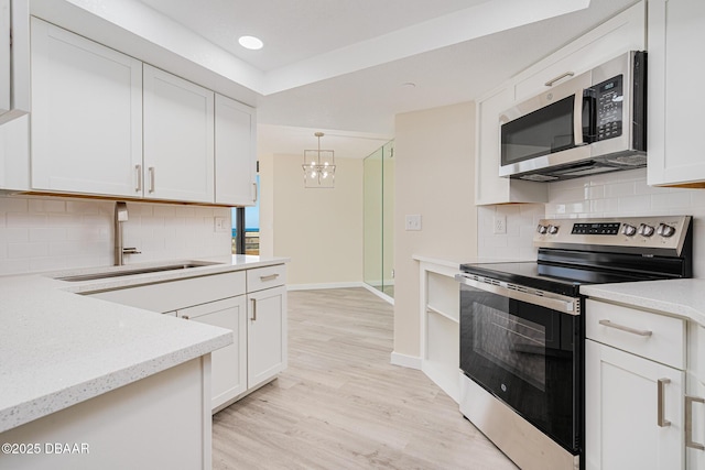 1 Oceans W Blvd Unit 7B5, Daytona Beach, FL 32118 - kitchen featuring a sink, a notable chandelier, light wood-style floors, stainless steel appliances, and white cabinetry