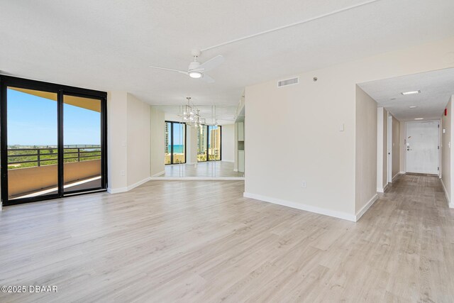 1 Oceans W Blvd Unit 7B5, Daytona Beach, FL 32118 - empty room featuring ceiling fan with notable chandelier, light wood-type flooring, visible vents, baseboards, and expansive windows