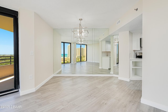 1 Oceans W Blvd Unit 7B5, Daytona Beach, FL 32118 - unfurnished dining area featuring visible vents, baseboards, a sink, light wood-style flooring, and a notable chandelier