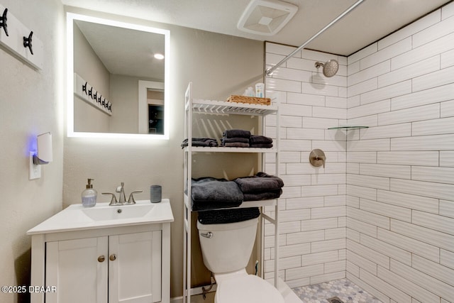 bathroom featuring tiled shower, vanity, and toilet