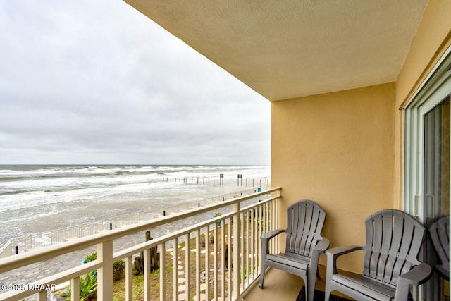 balcony featuring a water view and a view of the beach