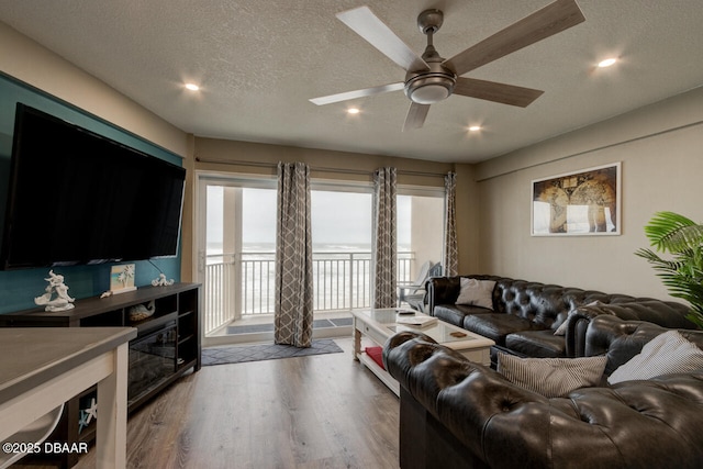 living room with ceiling fan, wood-type flooring, and a textured ceiling