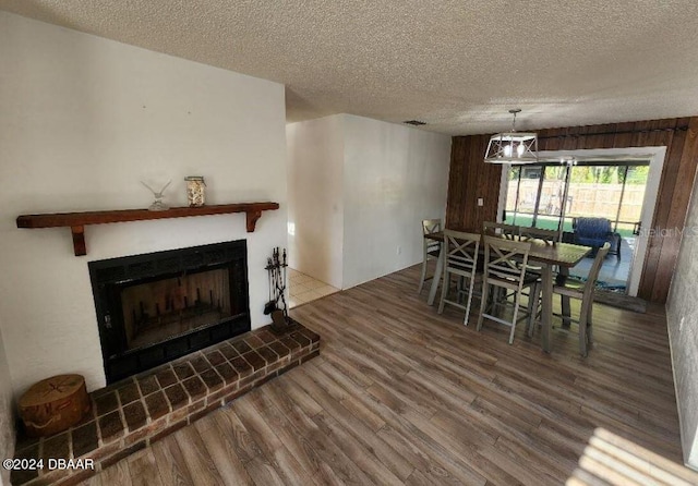 dining area featuring a brick fireplace, wood-type flooring, and a textured ceiling