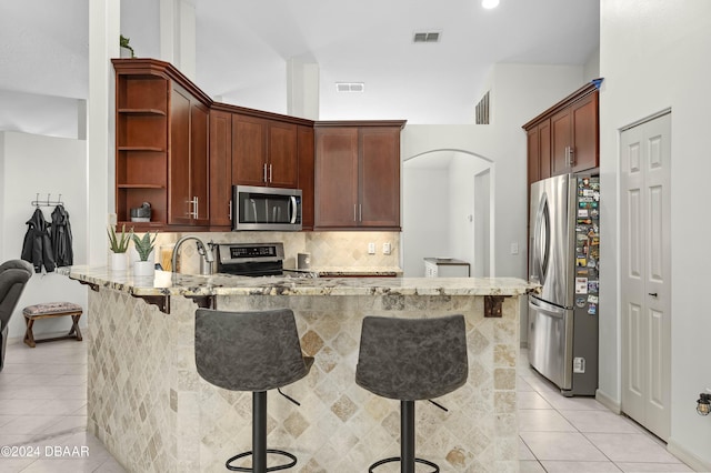 10 Pointing Pl, Palm Coast, FL 32164 - kitchen featuring appliances with stainless steel finishes, light tile patterned flooring, open shelves, light stone countertops, and a peninsula