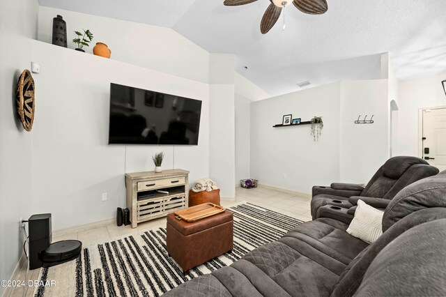 living room featuring light tile patterned flooring, ceiling fan, a textured ceiling, and lofted ceiling