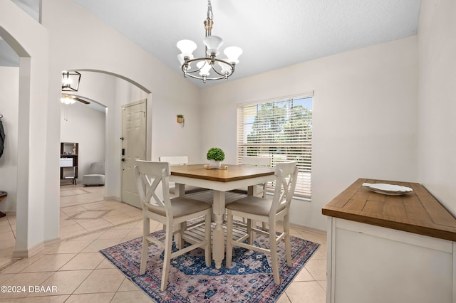 dining area featuring a textured ceiling, light tile patterned floors, and ceiling fan with notable chandelier