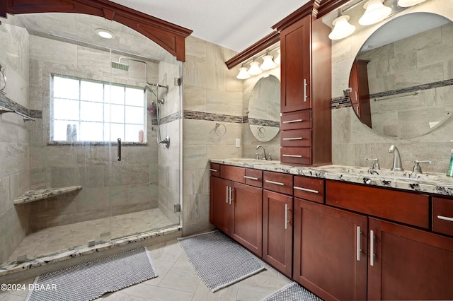 bathroom featuring a shower with shower door, vanity, tile patterned flooring, and tile walls