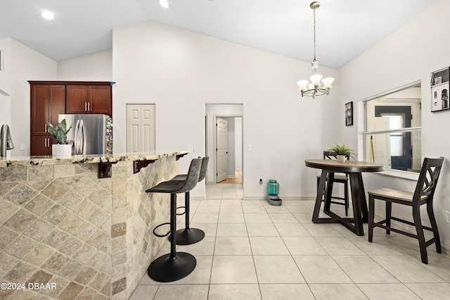 kitchen with stainless steel refrigerator, a breakfast bar, decorative light fixtures, a chandelier, and vaulted ceiling