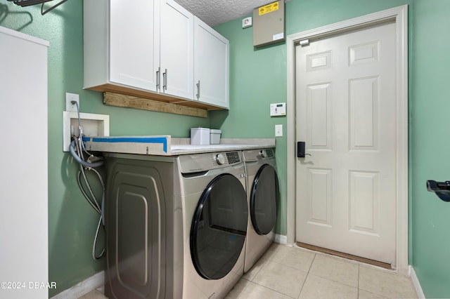 washroom with separate washer and dryer, cabinets, a textured ceiling, and light tile patterned flooring