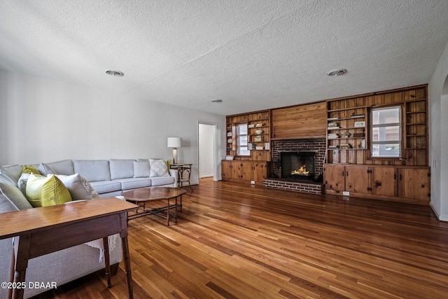 living room with dark hardwood / wood-style flooring, a fireplace, and a textured ceiling