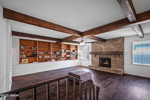 unfurnished living room featuring built in features, beam ceiling, dark hardwood / wood-style floors, a textured ceiling, and a brick fireplace