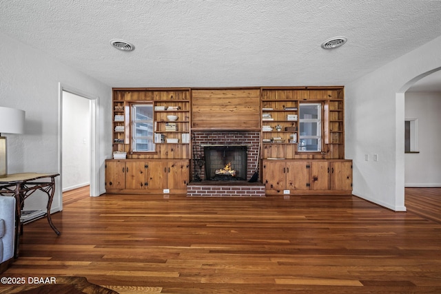 living room with dark hardwood / wood-style floors, a brick fireplace, and a textured ceiling