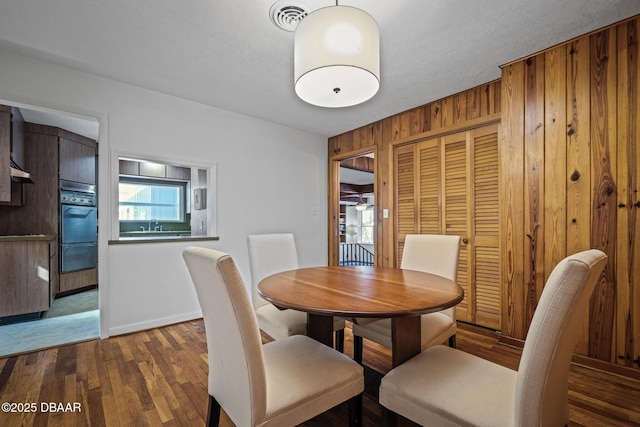 dining area featuring dark hardwood / wood-style floors and wood walls