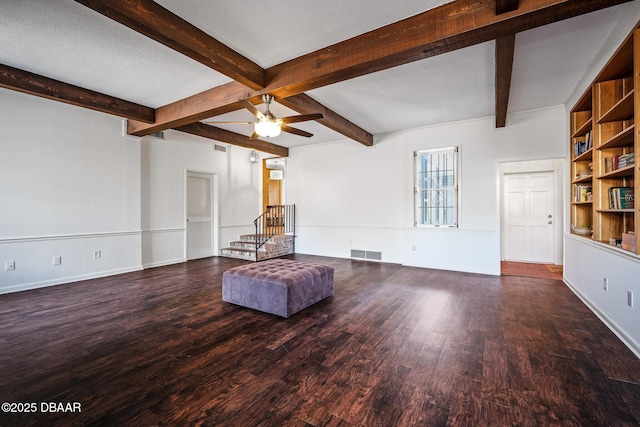 unfurnished room featuring ceiling fan, beamed ceiling, dark hardwood / wood-style floors, and a textured ceiling