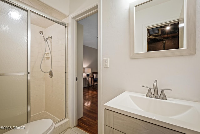 bathroom featuring a shower with door, vanity, hardwood / wood-style floors, and toilet