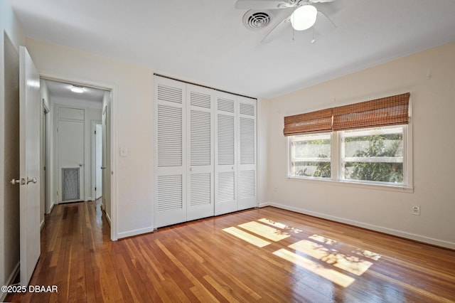 unfurnished bedroom with wood-type flooring, ceiling fan, and a closet