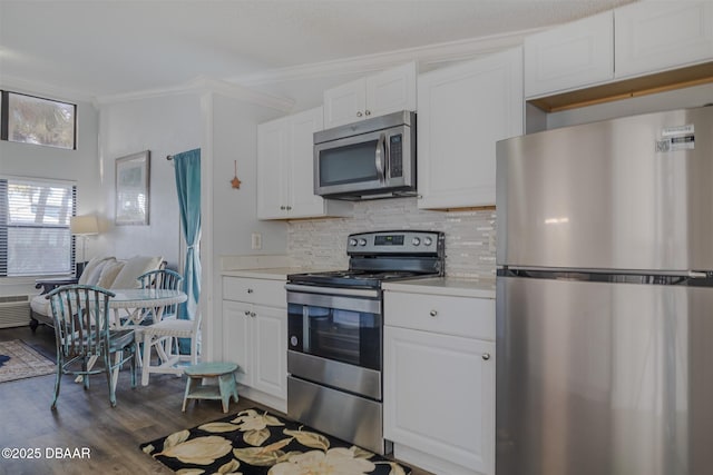 43 Jacaranda Cay Ct Unit 430, New Smyrna Beach, FL 32169 - kitchen featuring stainless steel appliances, dark wood-style flooring, white cabinetry, decorative backsplash, and crown molding