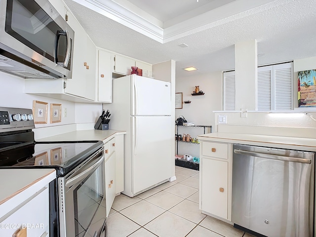 kitchen featuring appliances with stainless steel finishes, light tile patterned flooring, white cabinets, and light countertops