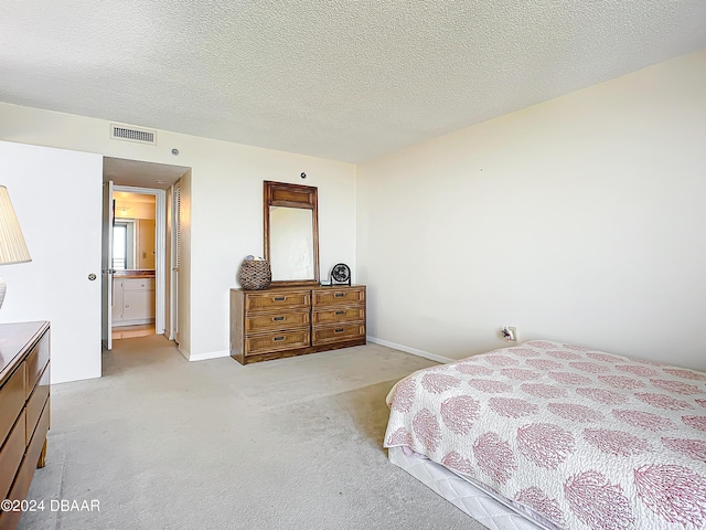 bedroom with a textured ceiling, baseboards, visible vents, and light carpet