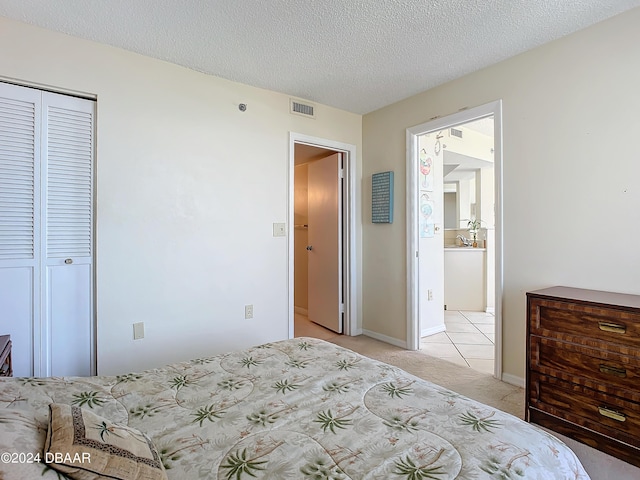 bedroom with visible vents, baseboards, light colored carpet, a closet, and a textured ceiling