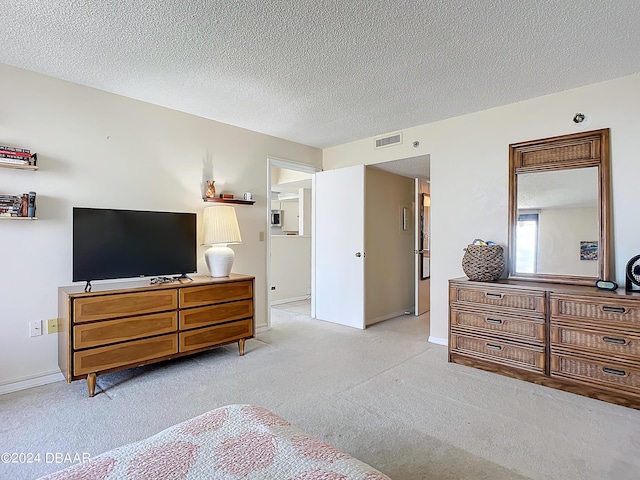 bedroom with visible vents, baseboards, light colored carpet, and a textured ceiling