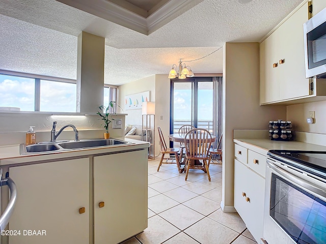 kitchen featuring light tile patterned flooring, a sink, appliances with stainless steel finishes, white cabinetry, and a notable chandelier