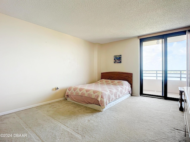 carpeted bedroom with expansive windows, baseboards, a textured ceiling, and access to exterior