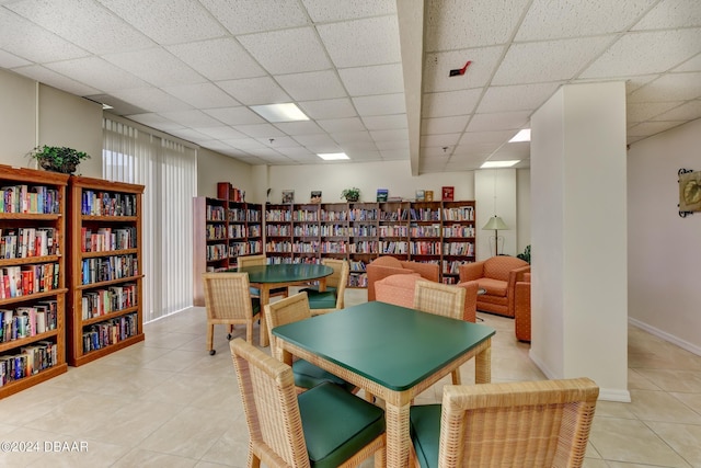 recreation room with light tile patterned flooring, a drop ceiling, and baseboards