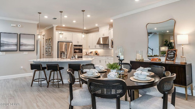 dining space with ornamental molding and light hardwood / wood-style flooring