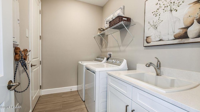 washroom featuring cabinets, sink, washer and dryer, and light wood-type flooring