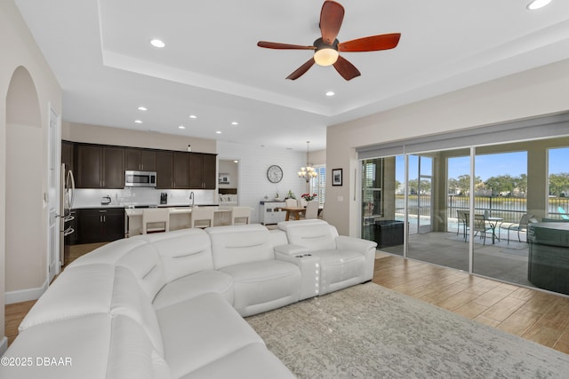 6871 Forkmead Ln, Port Orange, FL 32128 - living room featuring recessed lighting, ceiling fan, light wood finished floors, a chandelier, and a tray ceiling