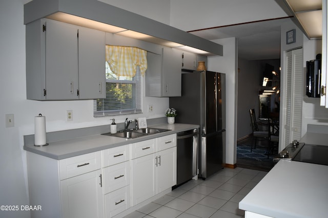 kitchen with a sink, white cabinetry, light countertops, light tile patterned floors, and dishwasher