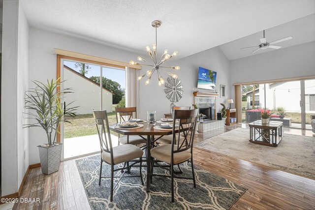 108 Shoal Creek Cir, Daytona Beach, FL 32114 - dining space featuring wood finished floors, vaulted ceiling, ceiling fan with notable chandelier, a fireplace, and baseboards