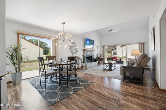 108 Shoal Creek Cir, Daytona Beach, FL 32114 - dining room featuring wood finished floors, ceiling fan with notable chandelier, a tile fireplace, and lofted ceiling