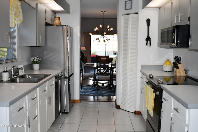 kitchen featuring light countertops, an inviting chandelier, light tile patterned flooring, black / electric stove, and a sink