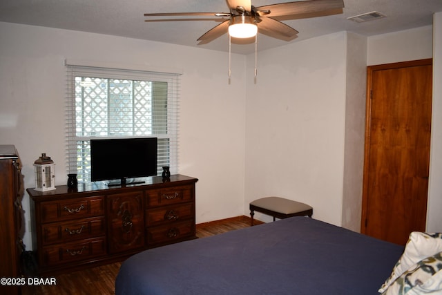 bedroom featuring visible vents, baseboards, dark wood-type flooring, and a ceiling fan