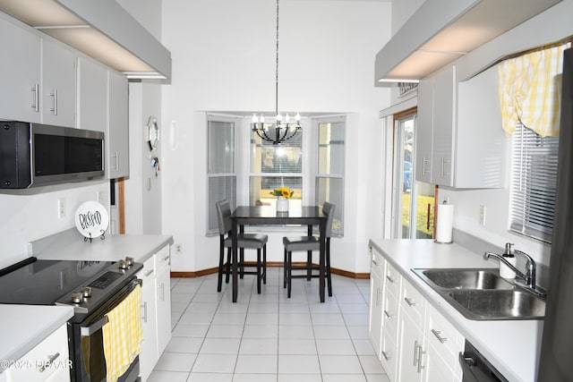 kitchen with a sink, stainless steel appliances, light countertops, white cabinets, and decorative light fixtures