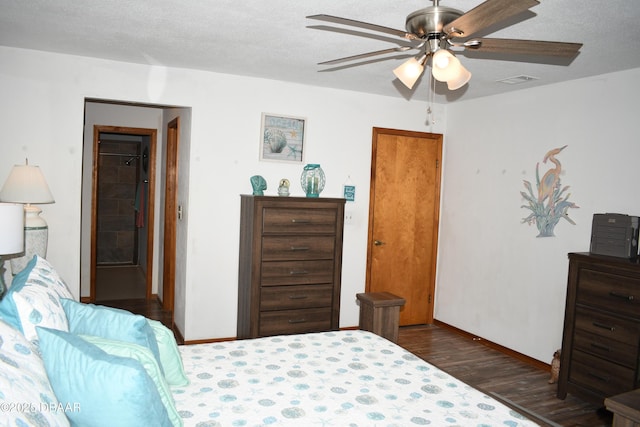 bedroom featuring dark wood finished floors, baseboards, visible vents, and a textured ceiling